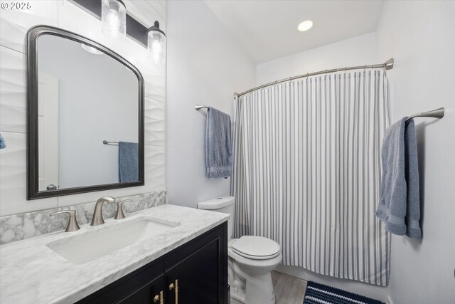 bathroom with curtained shower, vanity, and toilet