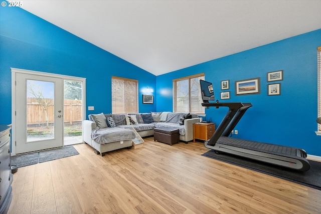 workout area featuring lofted ceiling and light wood-type flooring