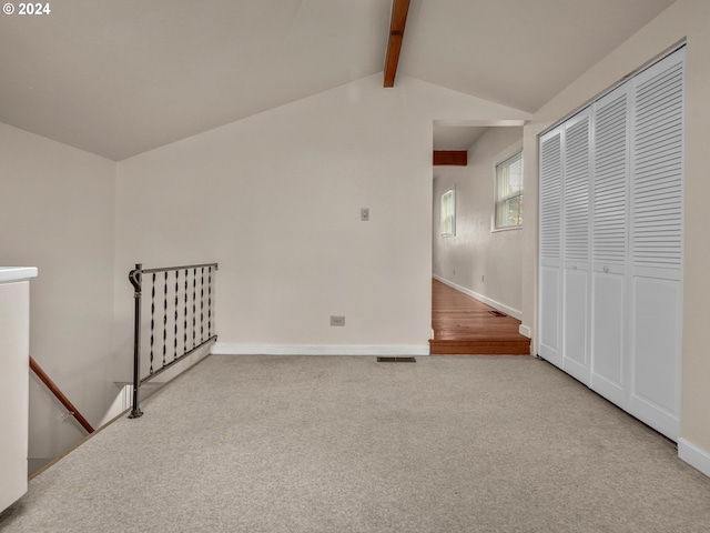 interior space with lofted ceiling with beams and light carpet