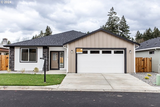 view of front of home with a garage, a shingled roof, fence, concrete driveway, and board and batten siding