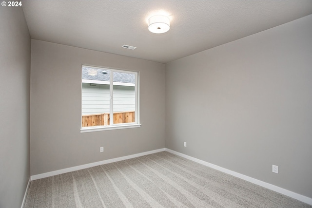 empty room with visible vents, light carpet, baseboards, and a textured ceiling