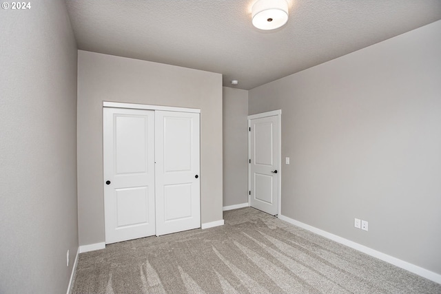 unfurnished bedroom featuring carpet floors, a textured ceiling, baseboards, and a closet