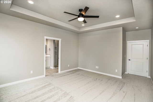 unfurnished bedroom with carpet floors, a raised ceiling, and baseboards