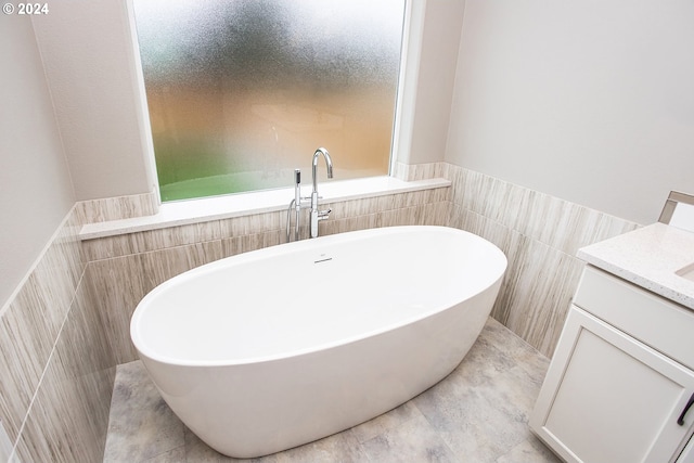 full bathroom featuring a wainscoted wall, a freestanding bath, tile walls, and vanity