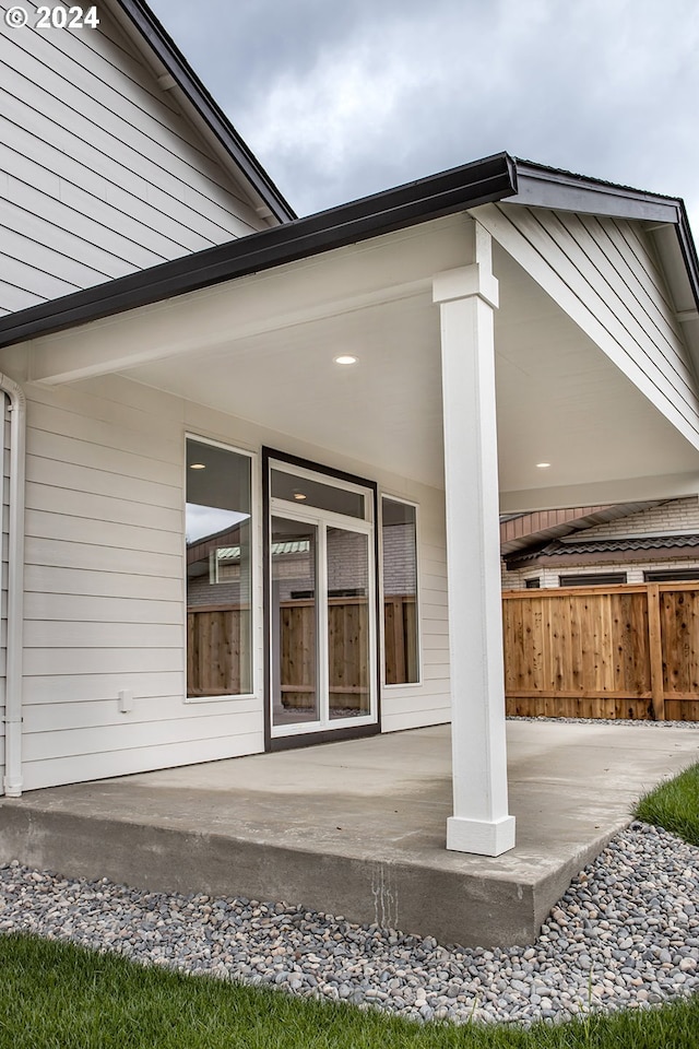 view of exterior entry with a patio and fence