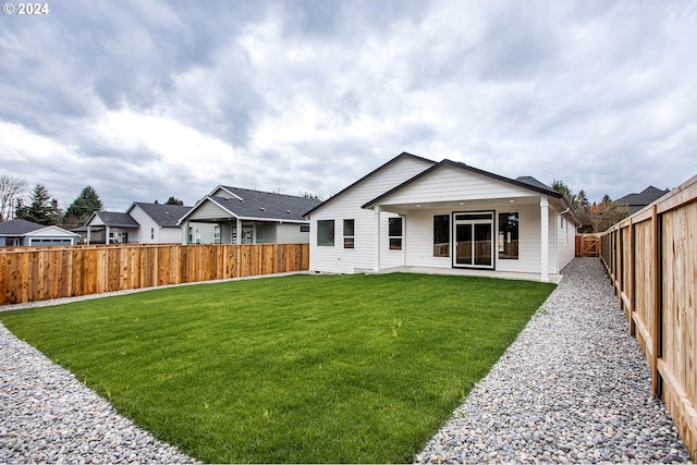 back of property featuring a fenced backyard, a residential view, and a lawn