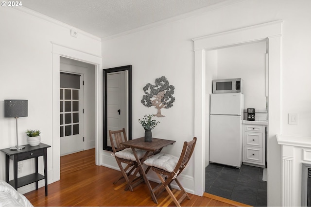 dining space featuring ornamental molding, dark hardwood / wood-style flooring, and a textured ceiling