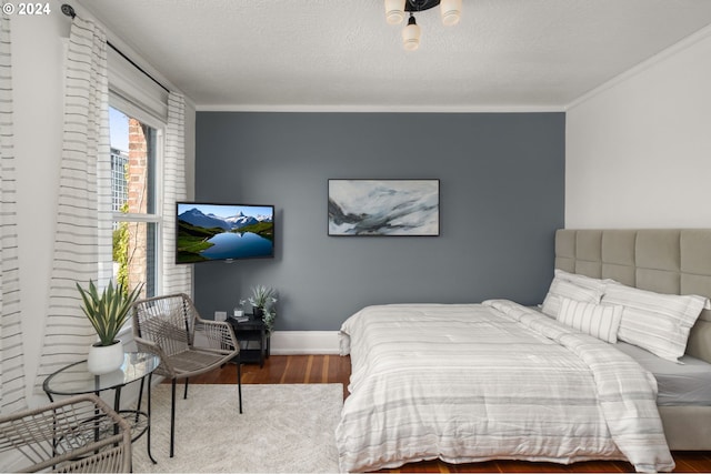 bedroom featuring hardwood / wood-style flooring, ornamental molding, and a textured ceiling