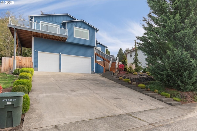 view of front facade featuring an attached garage, a balcony, driveway, stairway, and board and batten siding