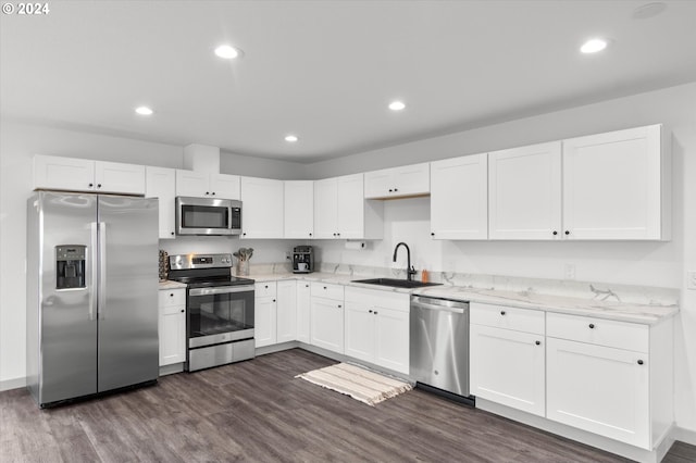 kitchen featuring dark wood-type flooring, sink, light stone counters, stainless steel appliances, and white cabinetry