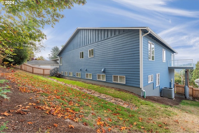 view of home's exterior featuring a balcony, a lawn, and central air condition unit