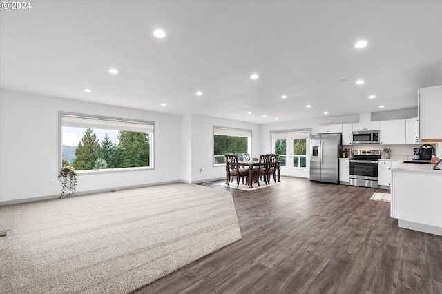 kitchen with stainless steel appliances, white cabinets, a wealth of natural light, and dark wood-type flooring