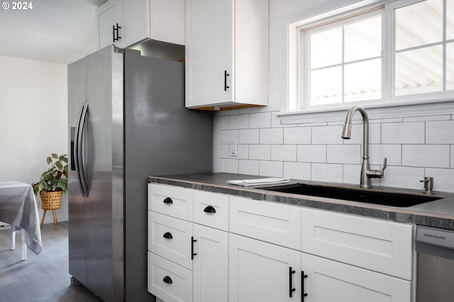 kitchen with tasteful backsplash, white cabinetry, sink, and appliances with stainless steel finishes