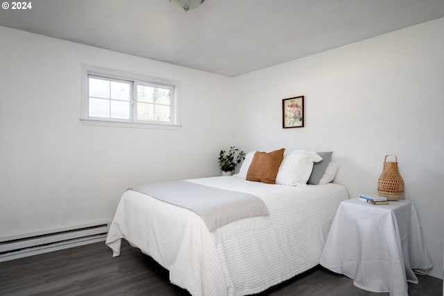 bedroom with dark hardwood / wood-style floors and a baseboard heating unit