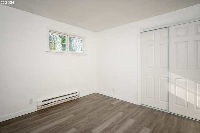 unfurnished bedroom with a closet, a baseboard radiator, and dark hardwood / wood-style floors