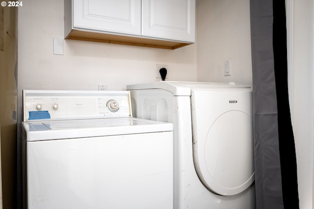 clothes washing area featuring washing machine and dryer and cabinets