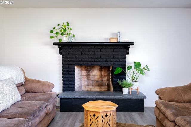 living room featuring wood-type flooring and a brick fireplace