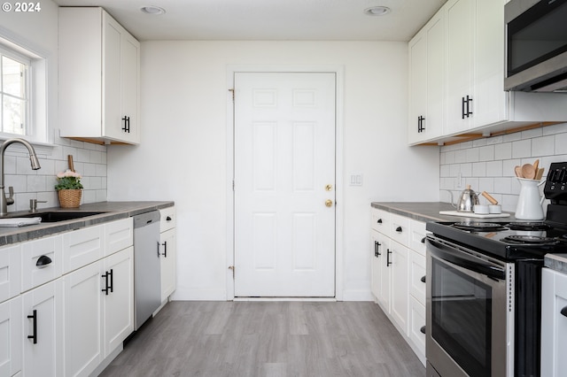 kitchen with sink, light hardwood / wood-style flooring, decorative backsplash, white cabinets, and appliances with stainless steel finishes