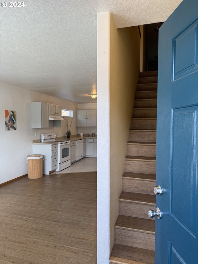 9845 N Lombard St, Portland, OR 97203 - staircase featuring wood finished floors, a textured ceiling, and baseboards