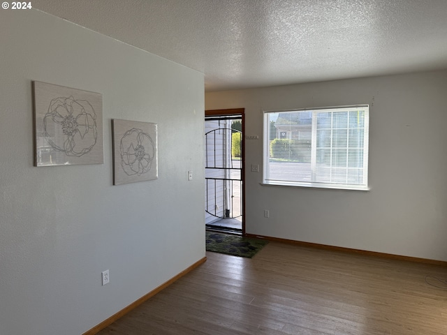 9845 N Lombard St, Portland, OR 97203 - spare room with wood finished floors, baseboards, and a textured ceiling