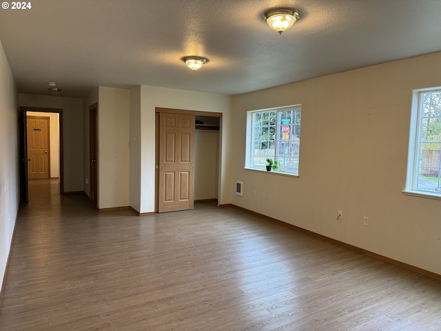 9845 N Lombard St, Portland, OR 97203 - unfurnished bedroom featuring multiple windows, wood finished floors, baseboards, a closet, and a textured ceiling