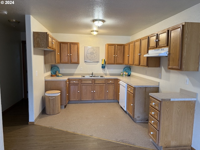 9845 N Lombard St, Portland, OR 97203 - kitchen with dishwasher, under cabinet range hood, brown cabinetry, a sink, and a textured ceiling