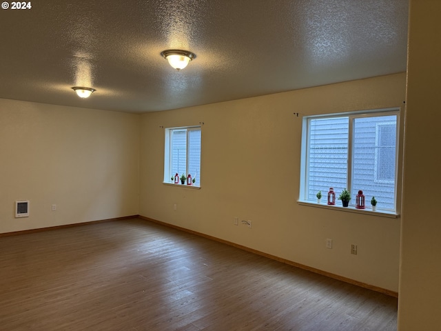 9845 N Lombard St, Portland, OR 97203 - spare room with a textured ceiling, wood finished floors, baseboards, and heating unit