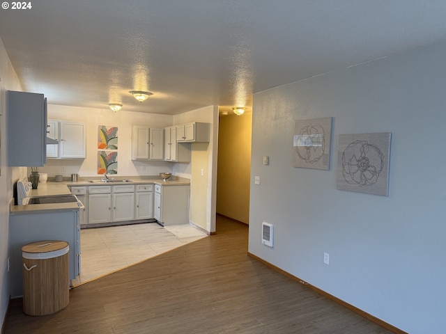 9845 N Lombard St, Portland, OR 97203 - kitchen with light wood-style flooring, baseboards, light countertops, and stove