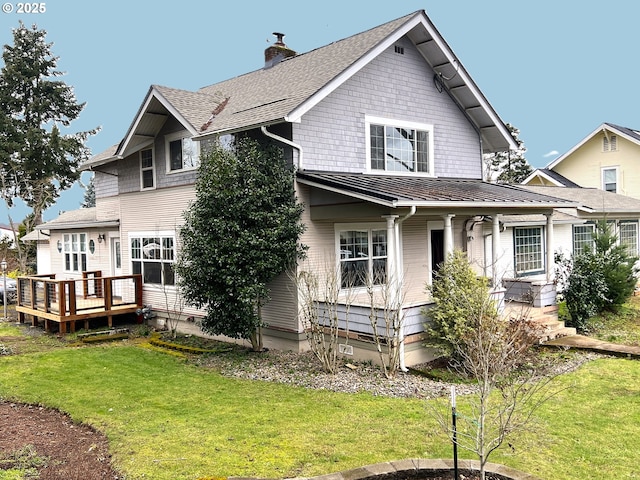 view of front of property featuring a standing seam roof, metal roof, a wooden deck, a chimney, and a front yard