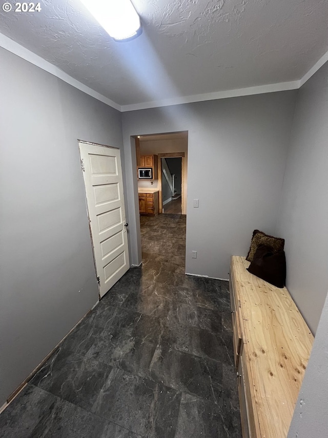 corridor with ornamental molding and a textured ceiling