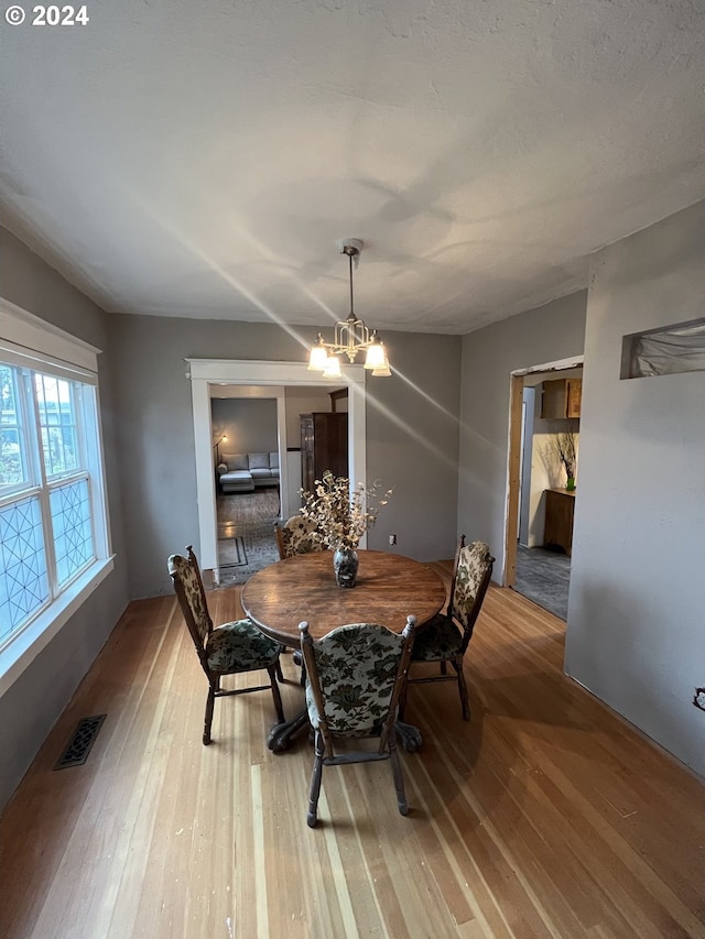 dining area featuring an inviting chandelier, visible vents, and wood finished floors