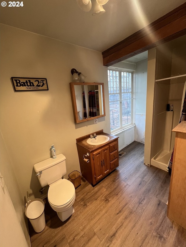 full bath featuring a stall shower, vanity, toilet, and wood finished floors