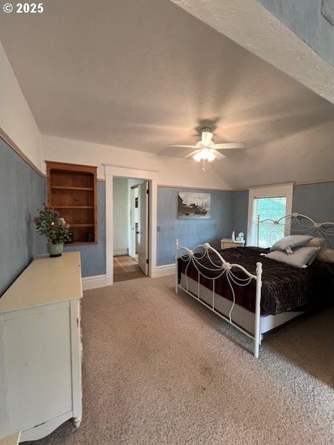 carpeted bedroom with lofted ceiling, a textured ceiling, a ceiling fan, and baseboards