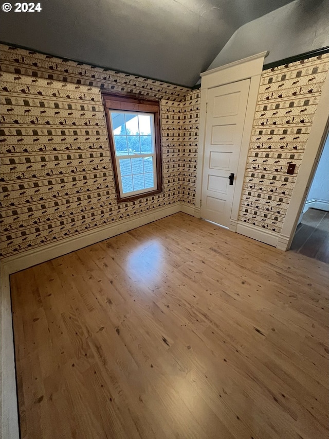 interior space with lofted ceiling, baseboards, and wood finished floors