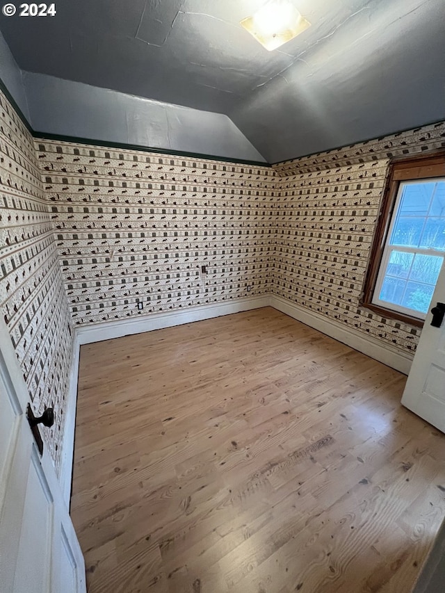 additional living space featuring lofted ceiling and light wood-style flooring