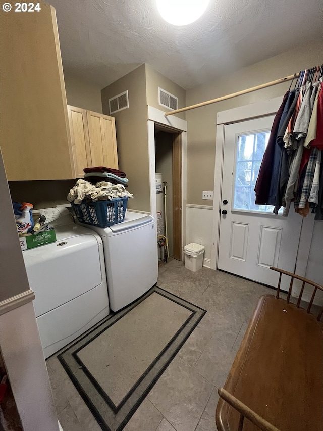 laundry area featuring cabinet space, visible vents, separate washer and dryer, and gas water heater