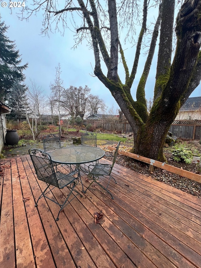 wooden terrace featuring outdoor dining space and a fenced backyard