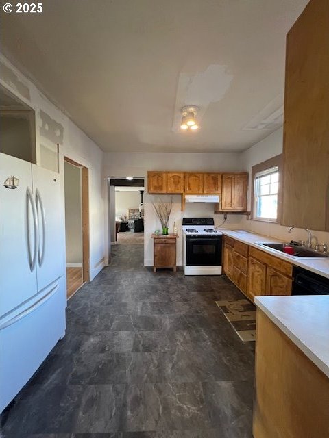 kitchen with light countertops, freestanding refrigerator, a sink, range, and under cabinet range hood