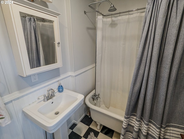 full bathroom with a wainscoted wall, shower / tub combo, tile patterned floors, a decorative wall, and a sink