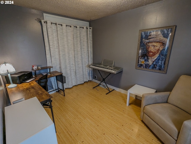 home office with light hardwood / wood-style flooring and a textured ceiling