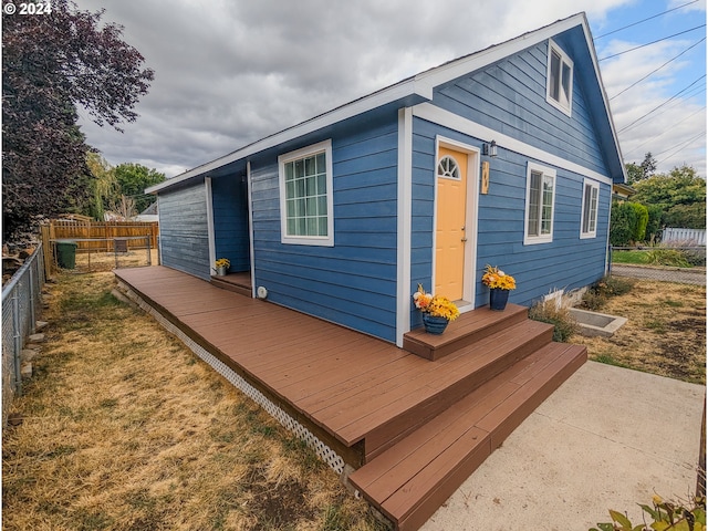 rear view of house featuring entry steps, a deck, and fence