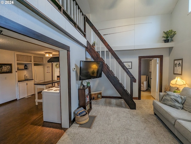 living room with stairway, dark wood-type flooring, and a towering ceiling