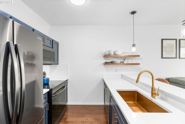 kitchen featuring appliances with stainless steel finishes, blue cabinetry, dark hardwood / wood-style floors, decorative light fixtures, and sink