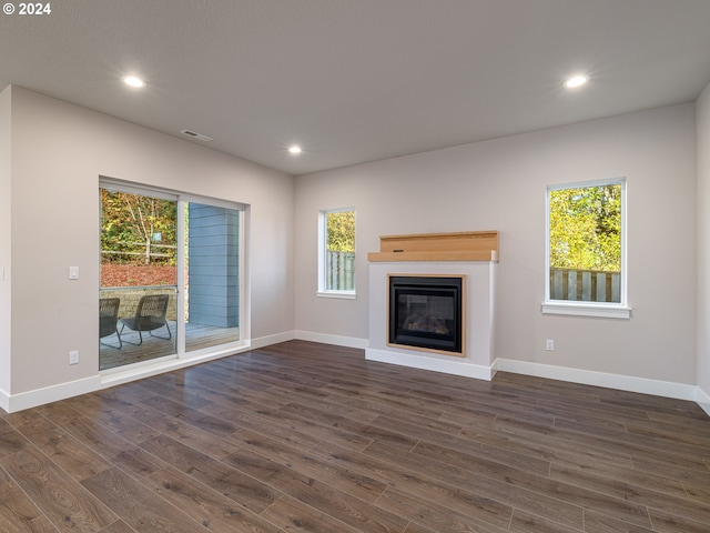 unfurnished living room featuring a wealth of natural light and dark wood-type flooring