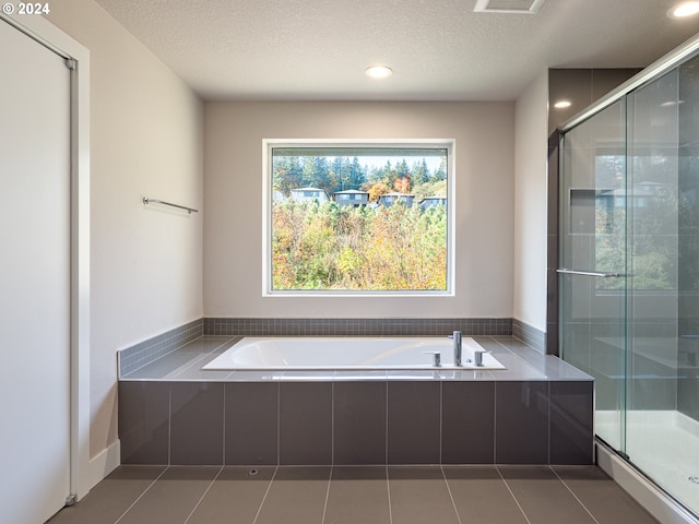 bathroom featuring tile patterned flooring, shower with separate bathtub, and a textured ceiling