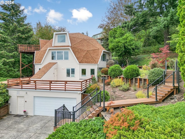 back of house featuring stairs, a garage, driveway, and a shingled roof