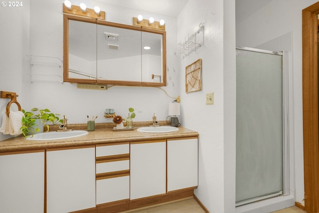 full bathroom with double vanity, visible vents, a stall shower, and a sink