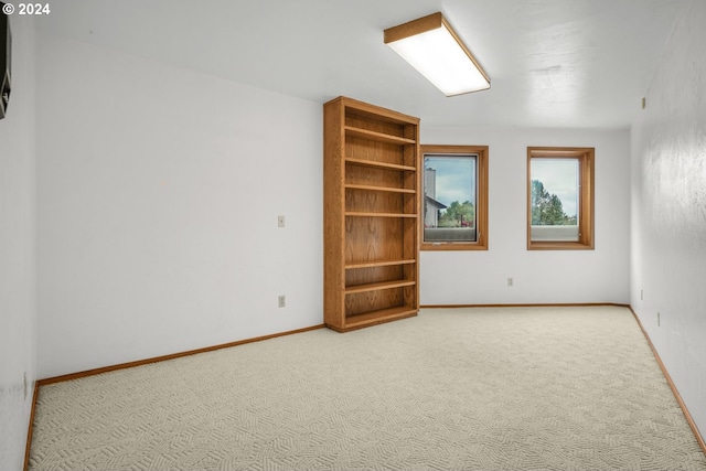 empty room featuring baseboards and light carpet