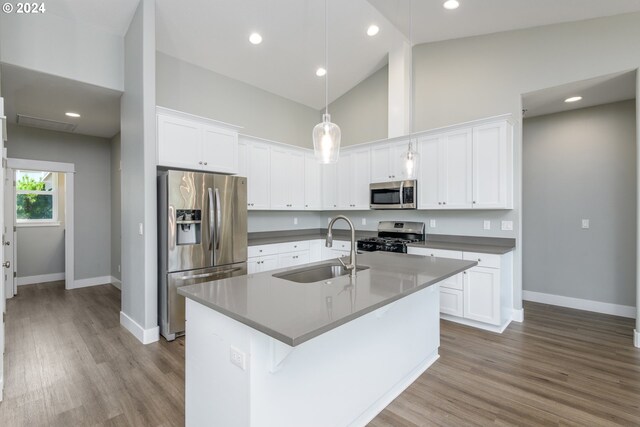 kitchen featuring decorative light fixtures, appliances with stainless steel finishes, white cabinetry, sink, and high vaulted ceiling