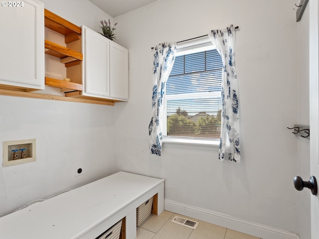 laundry area featuring a healthy amount of sunlight, hookup for a washing machine, light tile patterned floors, and cabinets